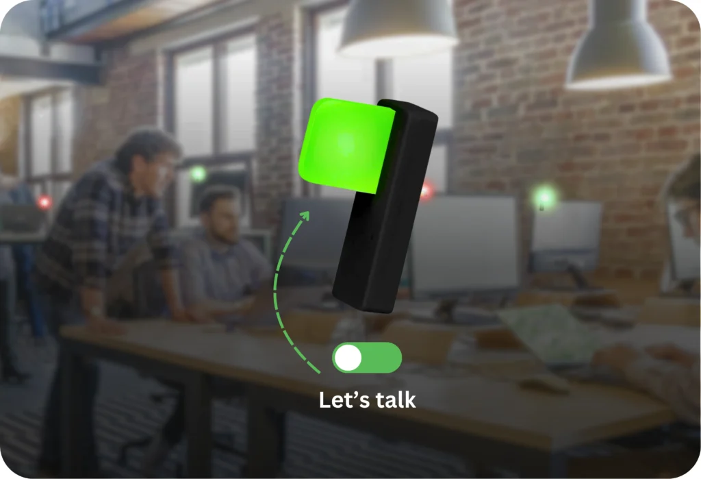 Luxafor Switch Pro 2 busy light glowing green in a busy open-plan office, with a toggle UI overlay showing "Let's talk" availability status and colleagues collaborating in the background